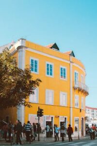 Colorful street scene in Lisbon showcasing a vibrant yellow building with pedestrians and clear skies.