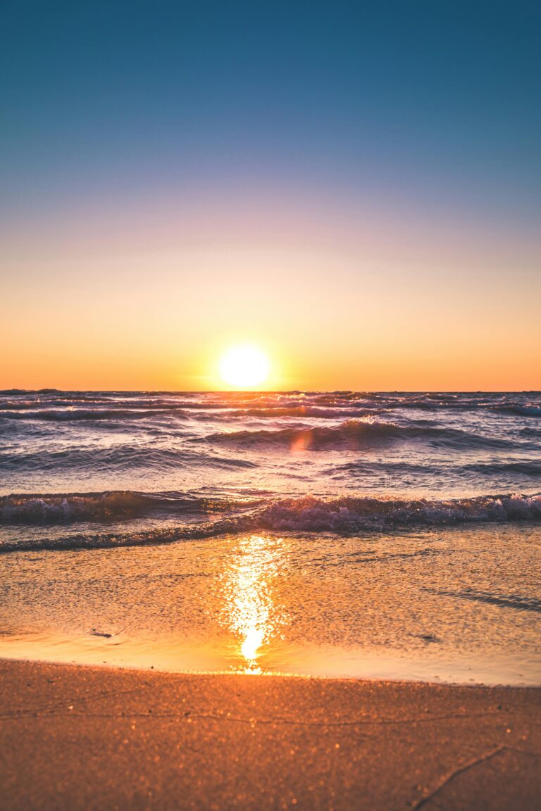 Experience the serene sunset over Ludington Beach with vibrant colors and tranquil waves.