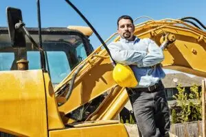 Business owner standing near construction equipment financed for business operations and growth.